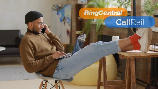 man with his feet on a desk, talking on a cell phone while using a laptop