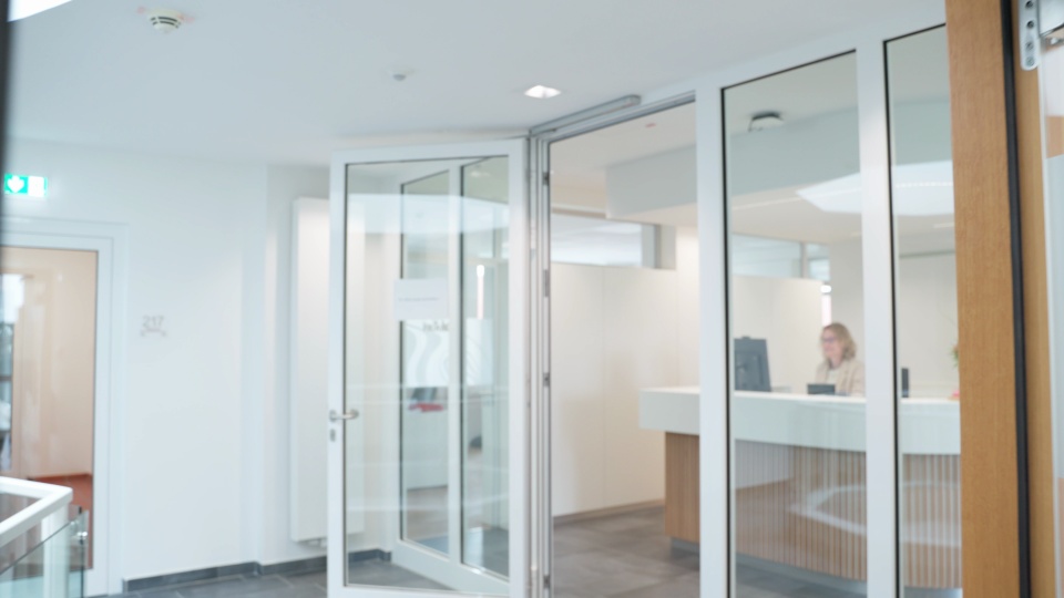 Still from the Etelser film: bright reception area with glass doors
