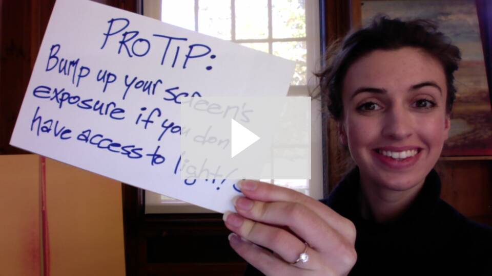 Video embed screenshot showing a person holding up a sign that says Pro Tip: Bump your screens exposure if you dont have access to light