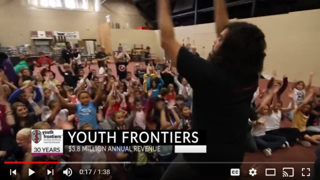 scene from youth frontiers testimonial video a staff member in front of a group of kids leading an activity