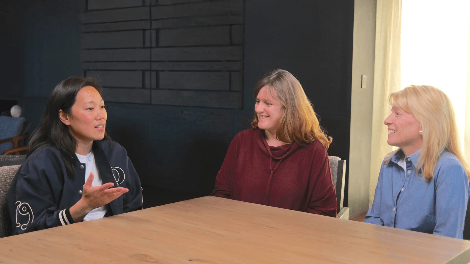 Three women are seated at a table talking.