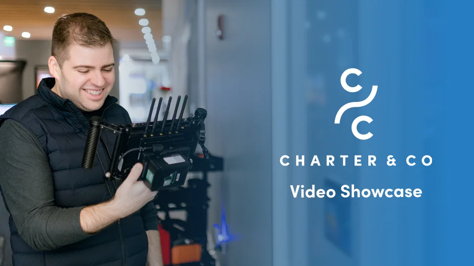 Drew English holding video production monitor with charter and co graphic